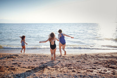 Three children of girls in swimsuits run on the sand and play on the beach. summer holidays