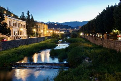 River amidst illuminated buildings against sky at dusk