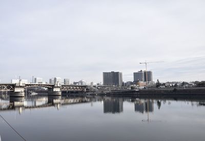 Buildings by river against sky in city