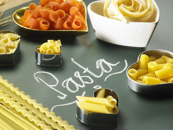 Raw pastas in containers and text on black background