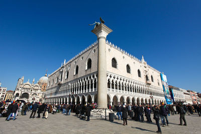 Group of people in historic building against clear blue sky