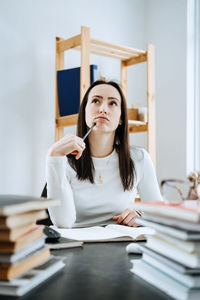 Female accountant working with many books and notepads on the background of laptop and calculator.