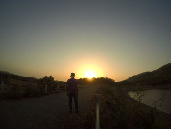 Silhouette of man standing on landscape against sunset