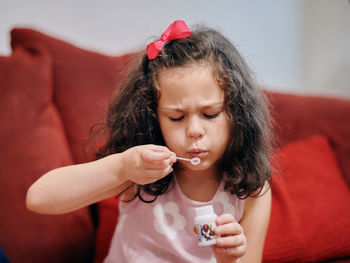 Young girl is blowing up soap bubbles in the living room