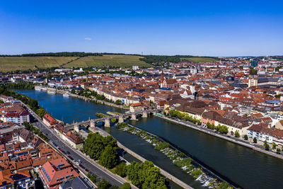 High angle view of townscape by river against blue sky