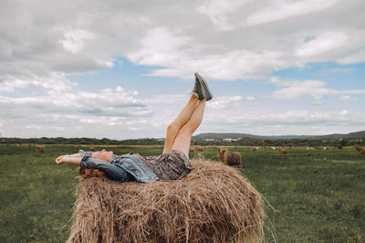 Man relaxing on field against sky