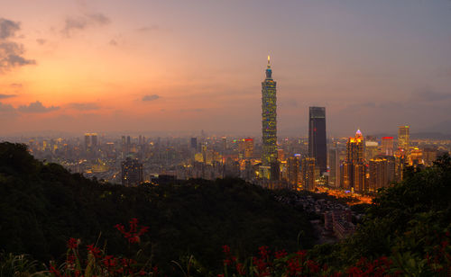 Illuminated cityscape against sky during sunset