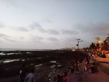 People on beach against sky at dusk