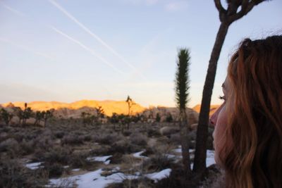 Portrait of woman on landscape against sky during sunset