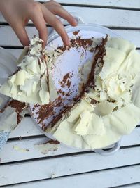 Cropped image of hand holding cake slice on table