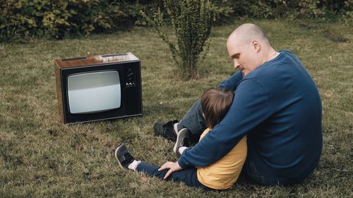 Rear view of men sitting on mobile phone