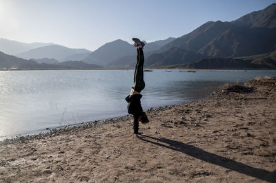 Woman hand standing on the shore of a lake while enjoying the nature landscape.