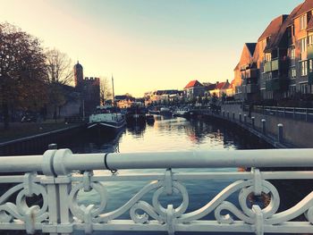 Bridge over river by buildings in city against clear sky