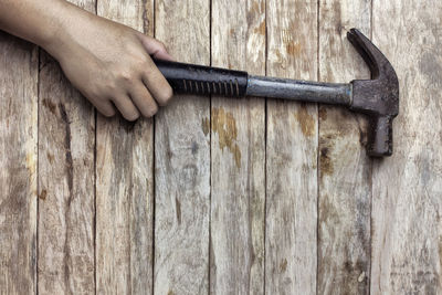 Cropped hand of person holding hammer on wooden table