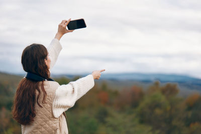 Rear view of woman with arms raised against sky