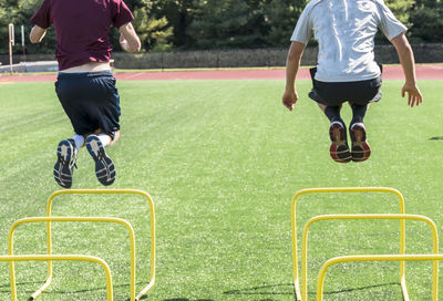 Rear view of people jumping over hurdles