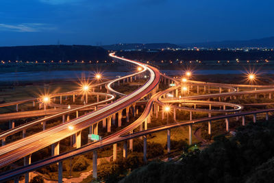 High angle view of light trails on bridges in city against sky at night