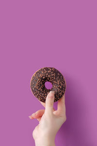 Low angle view of hand holding ice cream against pink background