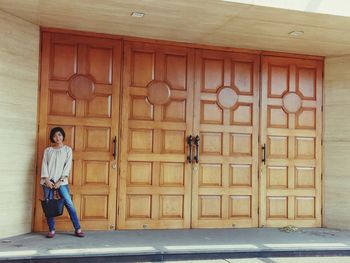 Full length of man standing against door of building