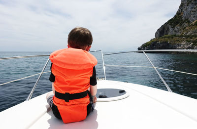 Rear view of boy on sea against sky