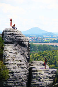 People standing on rock by mountain against sky