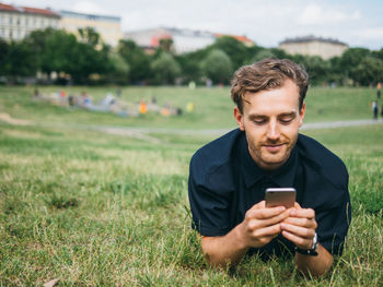 Young man using smart phone on field