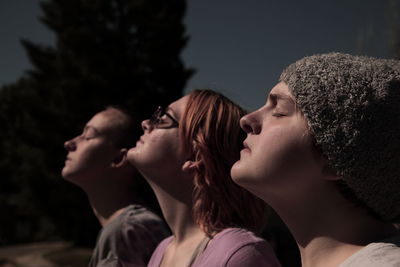 Sunlight falling on sisters with eyes closed during solar eclipse