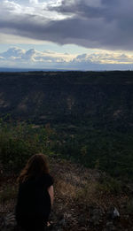 Rear view of woman looking at field against sky