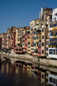 Residential buildings by river against sky