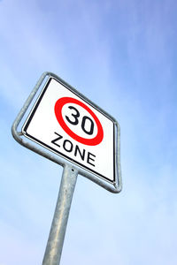 Low angle view of road sign against blue sky