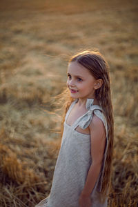 Girl child with long hair walking across the field wearing with long hair during sunset