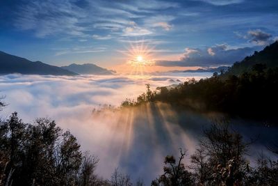 Scenic view of mountains against cloudy sky at sunset