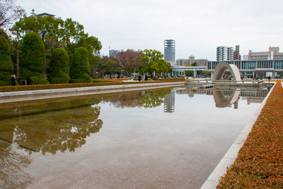 Swimming pool by lake against buildings in city against sky