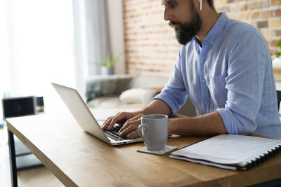 Midsection of businessman using laptop on table