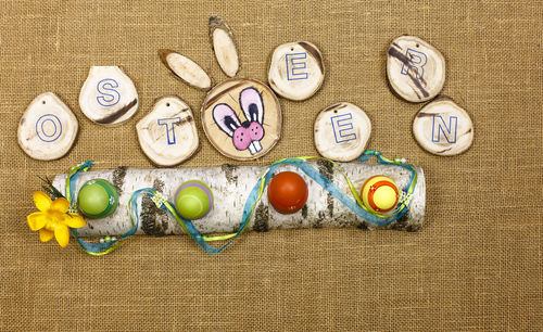 Directly above view of easter eggs and alphabet with rabbit head on jute