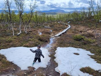 Rear view of boy walking on snow covered landscape