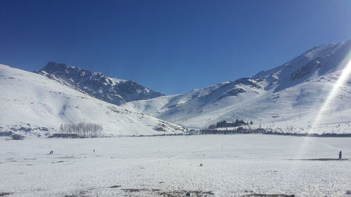 Scenic view of snowcapped mountains against clear blue sky