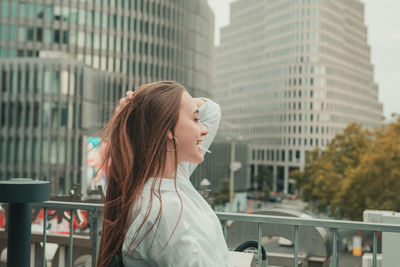 Side view of smiling young woman standing in city 
