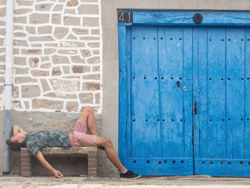 Full length of man relaxing on seat by house
