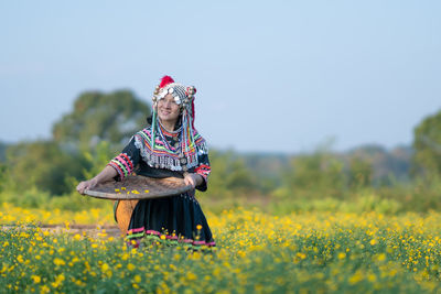 Woman standing on field with yellow flowers in background