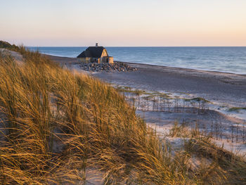 Solitary house on beach at sunset