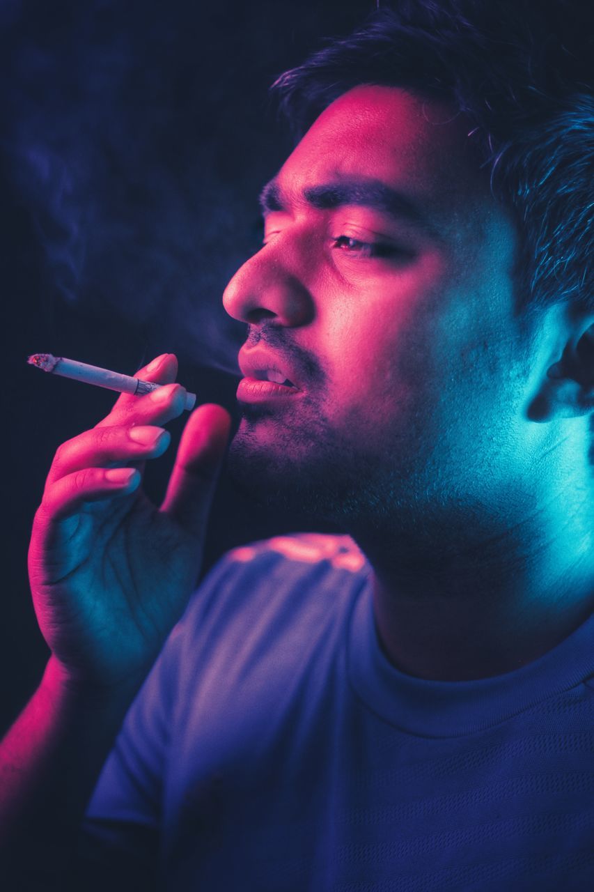 smoking - activity, cigarette, social issues, smoking issues, activity, smoke - physical structure, bad habit, one person, holding, warning sign, sign, leisure activity, real people, tobacco product, lifestyles, young men, risk, headshot