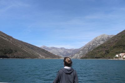 Rear view of woman looking at lake against mountains