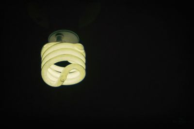 Low angle view of illuminated lamp against black background