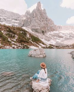 Full length of woman sitting on rock in lake