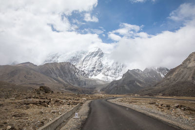 Road by mountains against sky