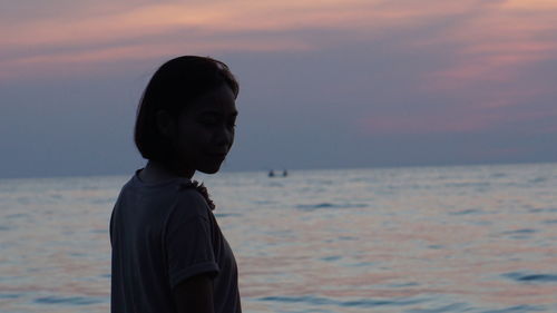 Woman standing by sea during sunset