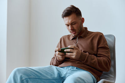 Young man using mobile phone while sitting on sofa at home