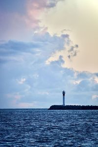 Lighthouse by sea against sky