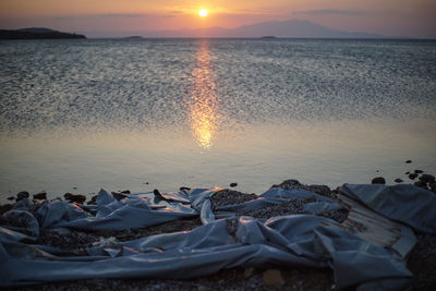 Scenic view of sea against sky during sunset, with a destroyed rescue boat in the forfront.